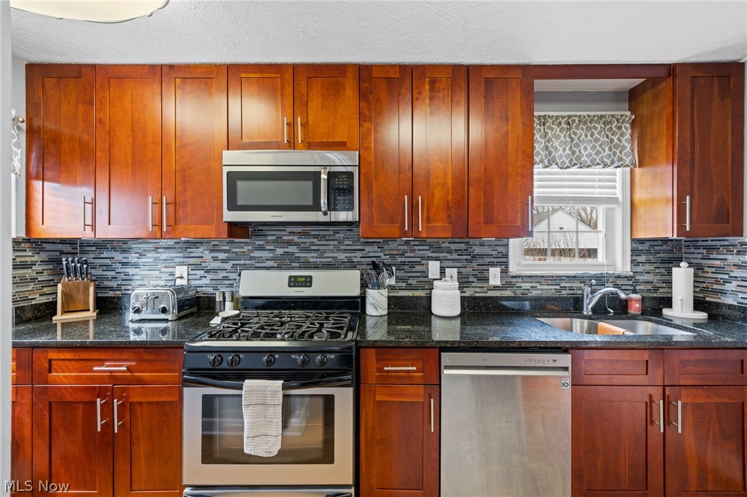 2368 Ashurst Road Cleveland, OH 44118 - Photo 7 of 20 Kitchen with appliances with stainless steel finishes, sink, backsplash, and dark stone counters