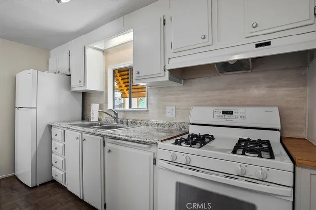 a kitchen with granite countertop cabinets and white appliances