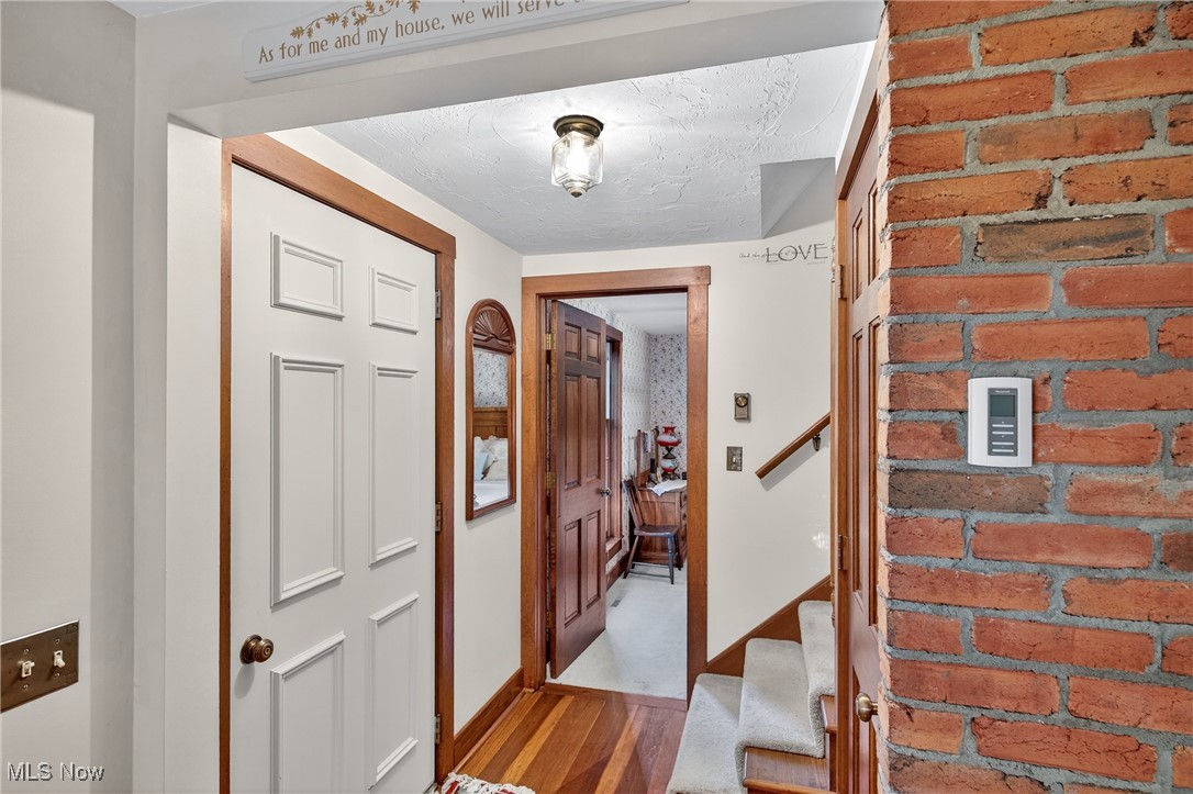 25700 Winona Road Homeworth, OH 44634 - Photo 14 of 49 Entryway with light wood finished floors, stairway, and brick wall