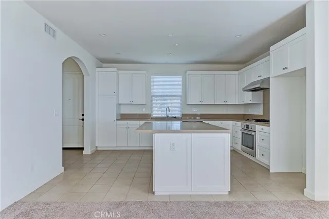 a kitchen with stainless steel appliances granite countertop a stove top oven a refrigerator a sink and dishwasher with white cabinets