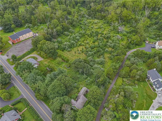an aerial view of residential house with outdoor space and trees all around