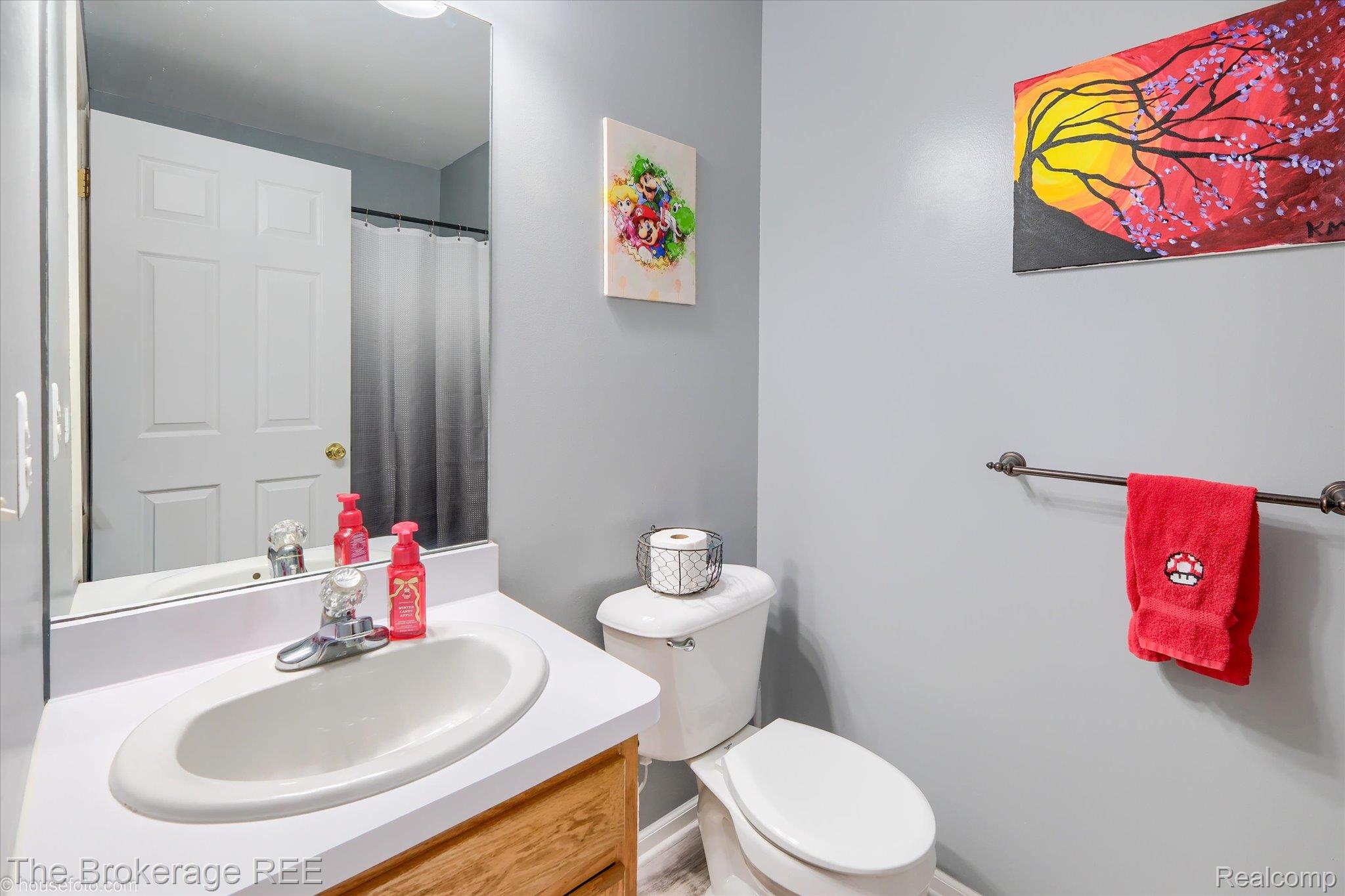 4432 North Belsay Road Flint, MI 48506 - Photo 55 of 79 Bathroom featuring a wood-finish vanity with a white countertop and integrated oval sink, a wall-mounted mirror, and a toilet