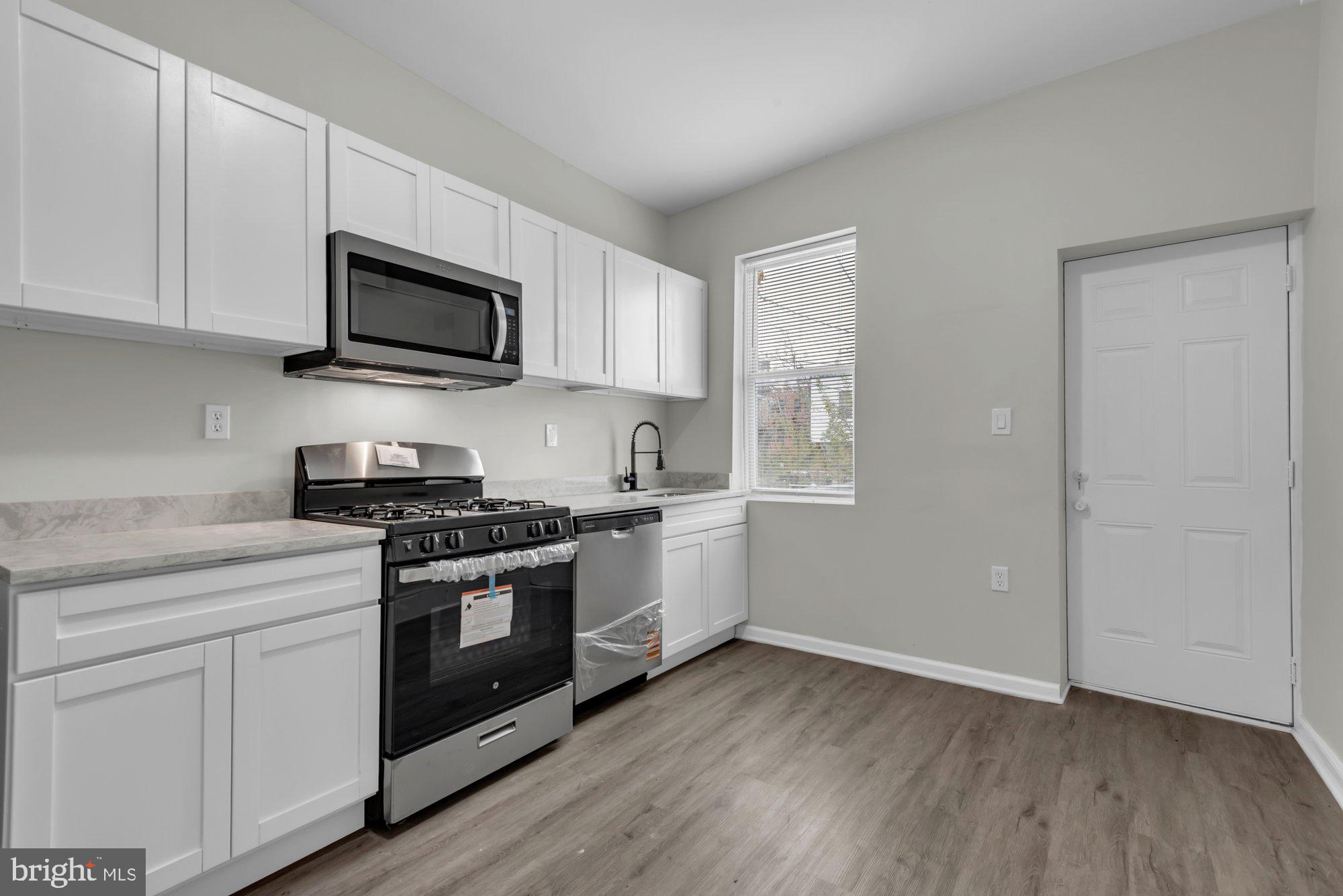 1904 Kennedy Avenue Baltimore, MD 21218 - Photo 12 of 29 a kitchen with stainless steel appliances granite countertop white cabinets a sink a stove a microwave and hard wood floors