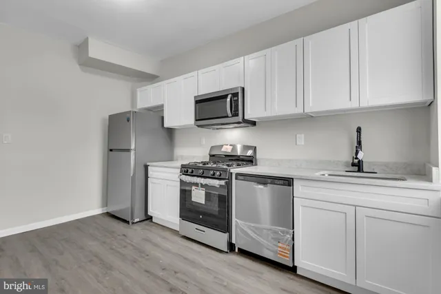 a kitchen with cabinets stainless steel appliances and wooden floor