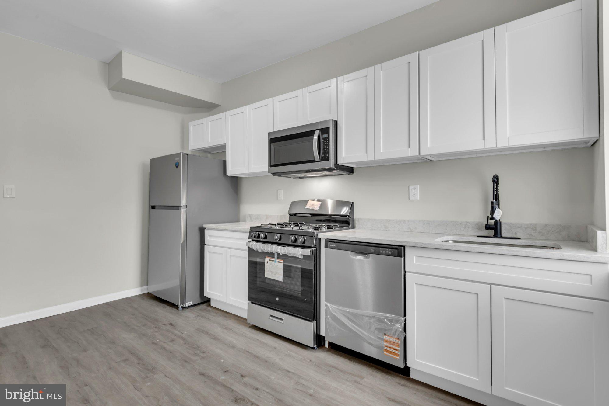 1904 Kennedy Avenue Baltimore, MD 21218 - Photo 13 of 29 a kitchen with cabinets stainless steel appliances and wooden floor