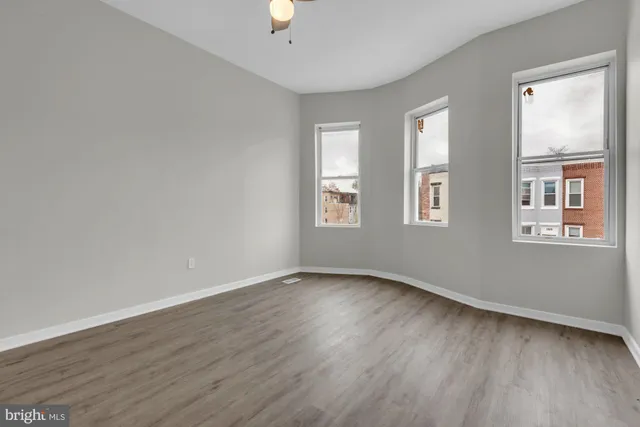 an empty room with wooden floor and windows