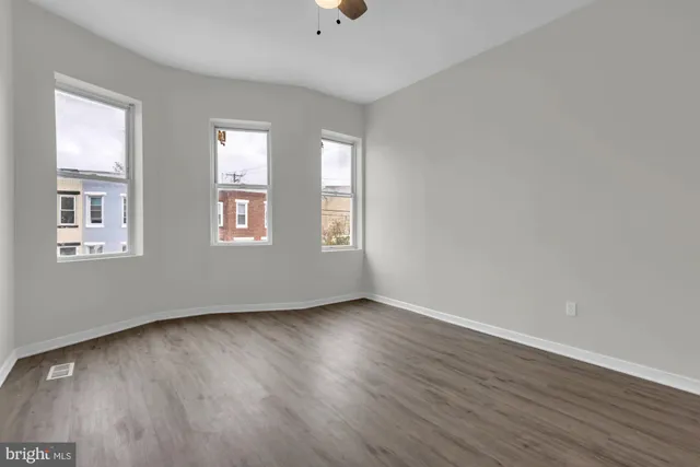 an empty room with wooden floor and windows