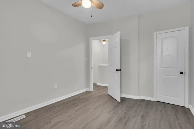 an empty room with wooden floor and a ceiling fan