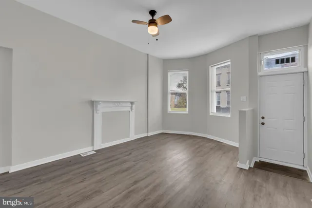 a view of an empty room with a window and wooden floor