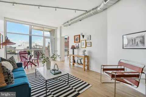 a living room with furniture a wooden floor and next to a window