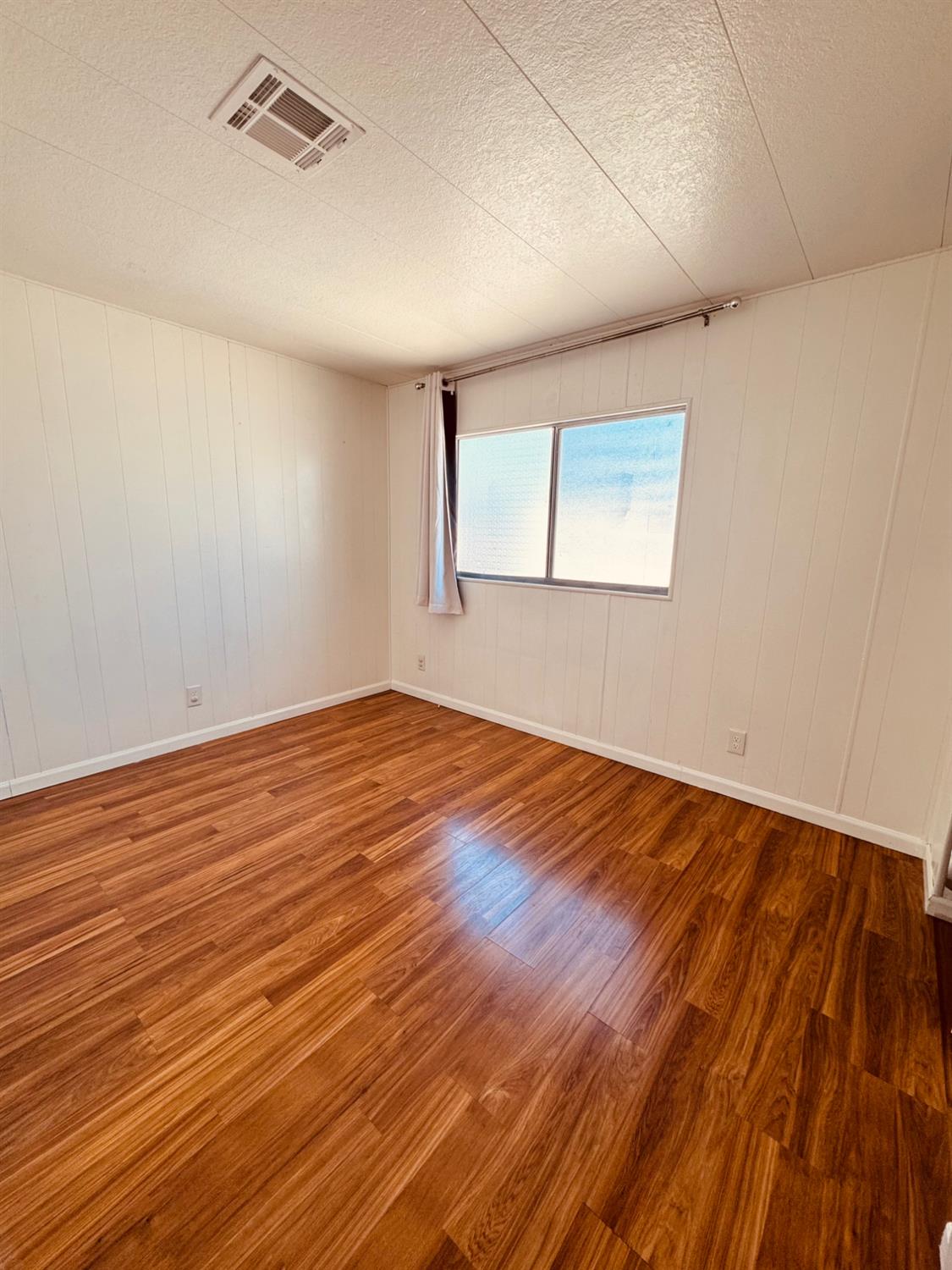 260 West Comet Road Gustine, CA 95322 - Photo 11 of 20 an empty room with wooden floor and windows