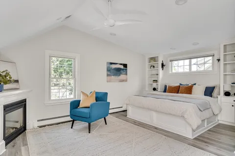 a bedroom with a bed a chair and a fireplace