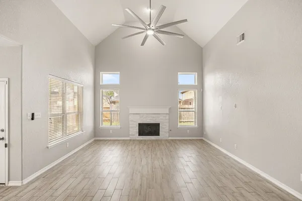 a view of an empty room with a window and wooden floor