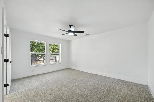 an empty room with windows and ceiling fan
