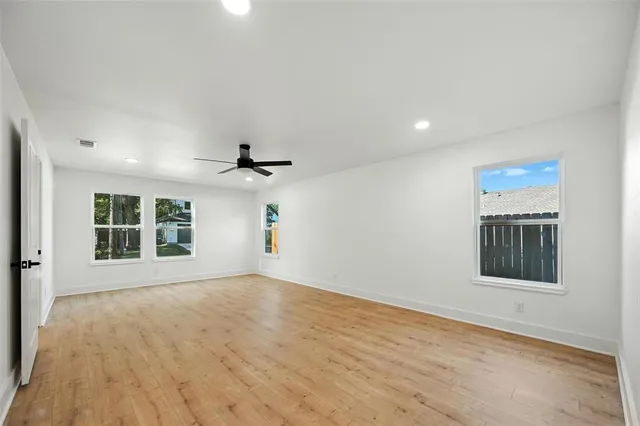 a view of an empty room with a window and wooden floor