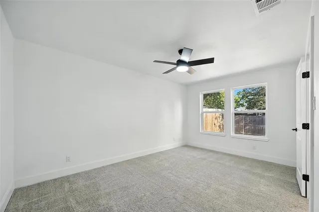 an empty room with windows and ceiling fan