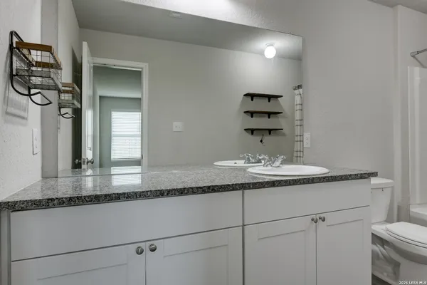 a bathroom with a granite countertop sink and a mirror