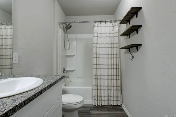 a bathroom with a granite countertop sink toilet and shower