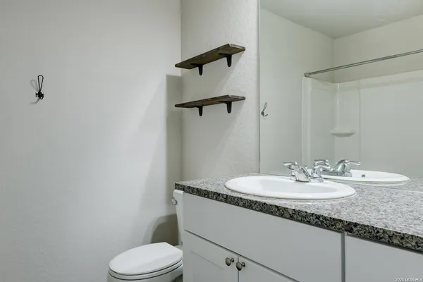 a bathroom with a granite countertop sink toilet and mirror