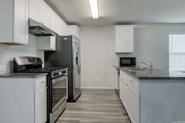 a kitchen with granite countertop a sink stove and refrigerator