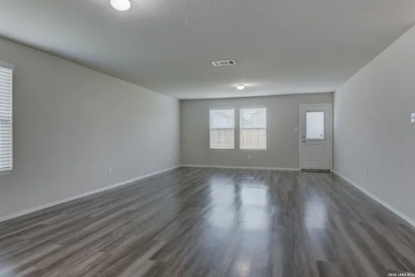 an empty room with wooden floor and windows