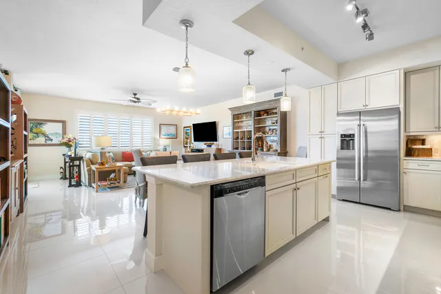 a kitchen with stainless steel appliances kitchen island granite countertop a table chairs and a refrigerator