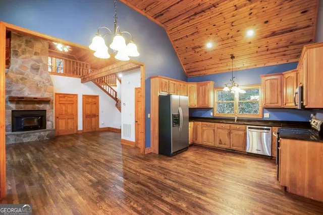 a kitchen with stainless steel appliances granite countertop a refrigerator a sink and white cabinets