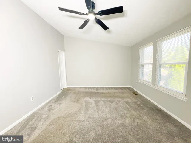 an empty room with a window and a fan