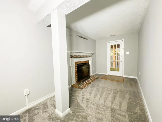 a view of an empty room with a fireplace and a window