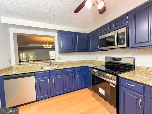 a kitchen with stainless steel appliances granite countertop wooden cabinets a stove top oven a sink and dishwasher