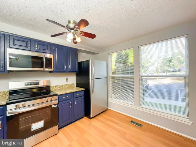 a kitchen with stainless steel appliances granite countertop a refrigerator a stove top oven a sink with a dining table and chairs