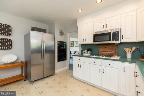 a kitchen with stainless steel appliances granite countertop a refrigerator a stove a sink and white cabinets
