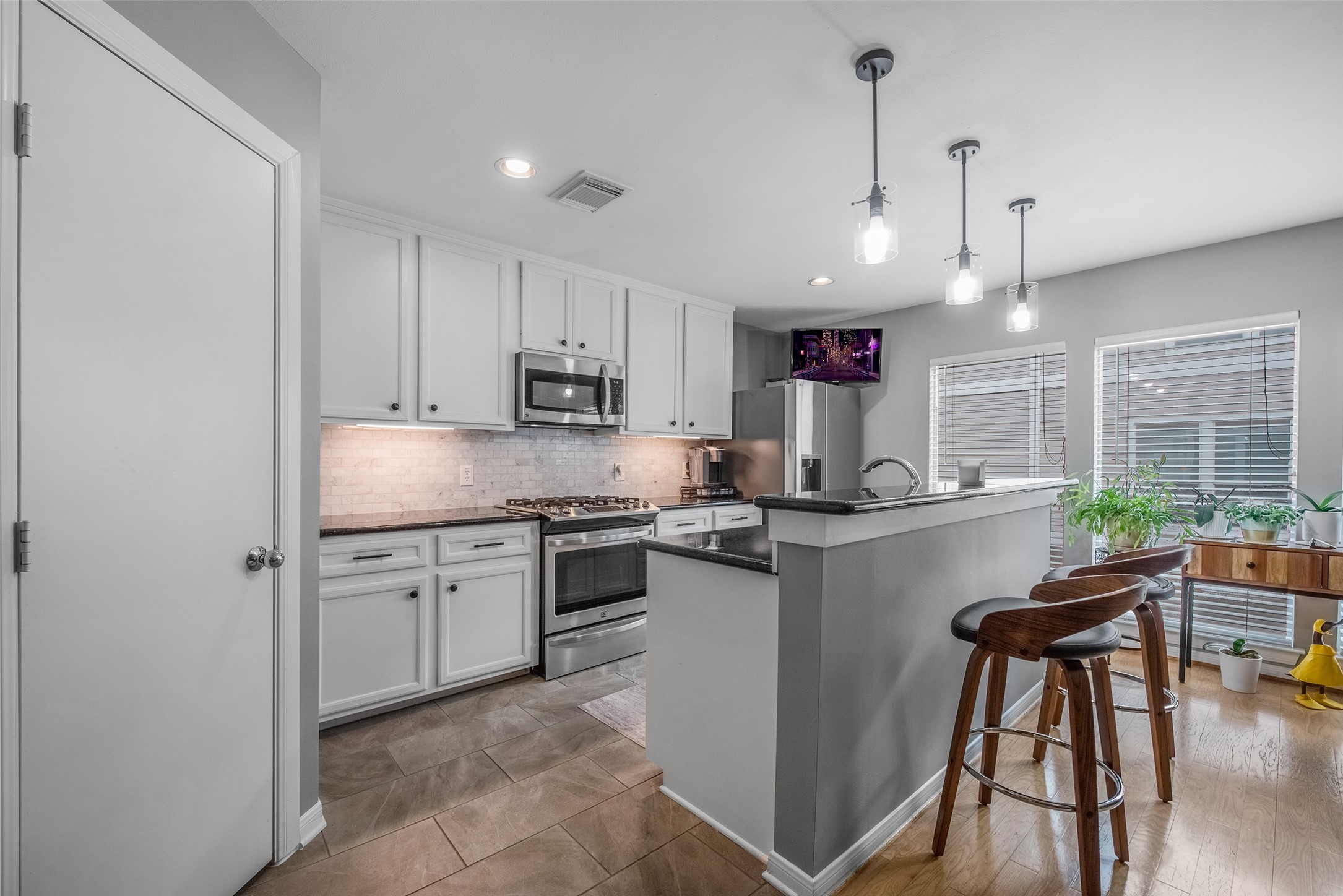 1028 La Rue Street Houston, TX 77019 - Photo 4 of 29 This modern kitchen features sleek white cabinets, stainless steel appliances, and a stylish tile backsplash.