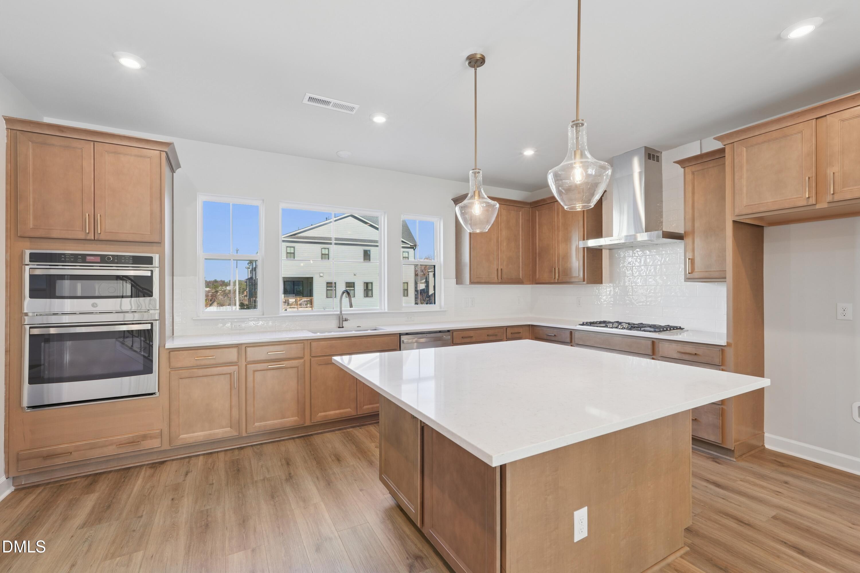 4607 Mint Leaf Lane Raleigh, NC 27612 - Photo 3 of 17 a large kitchen with kitchen island a stove a sink a center island and wooden floor