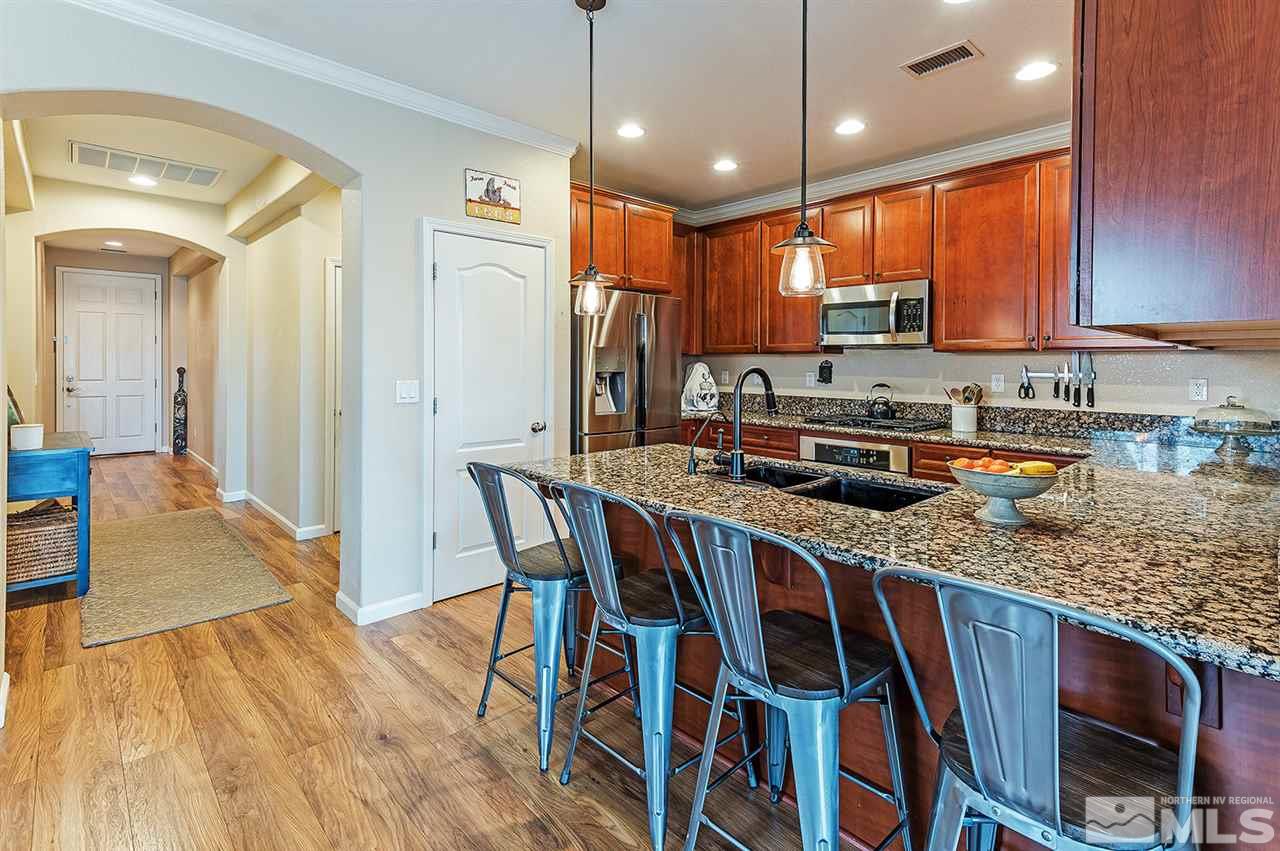 395 Sondrio Way Reno, NV 89521 - Photo 9 of 25 a kitchen with stainless steel appliances granite countertop a kitchen island a stove a refrigerator a sink a dining table and chairs with wooden floor