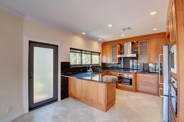 a kitchen with stainless steel appliances granite countertop a refrigerator a stove and a sink with wooden floor