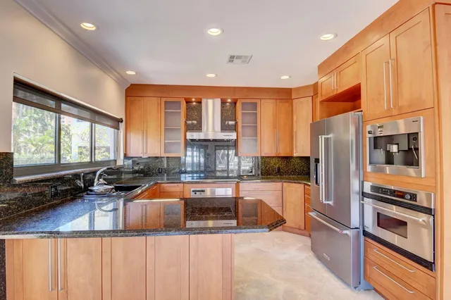 a kitchen with stainless steel appliances granite countertop a refrigerator a stove and a sink with wooden cabinets