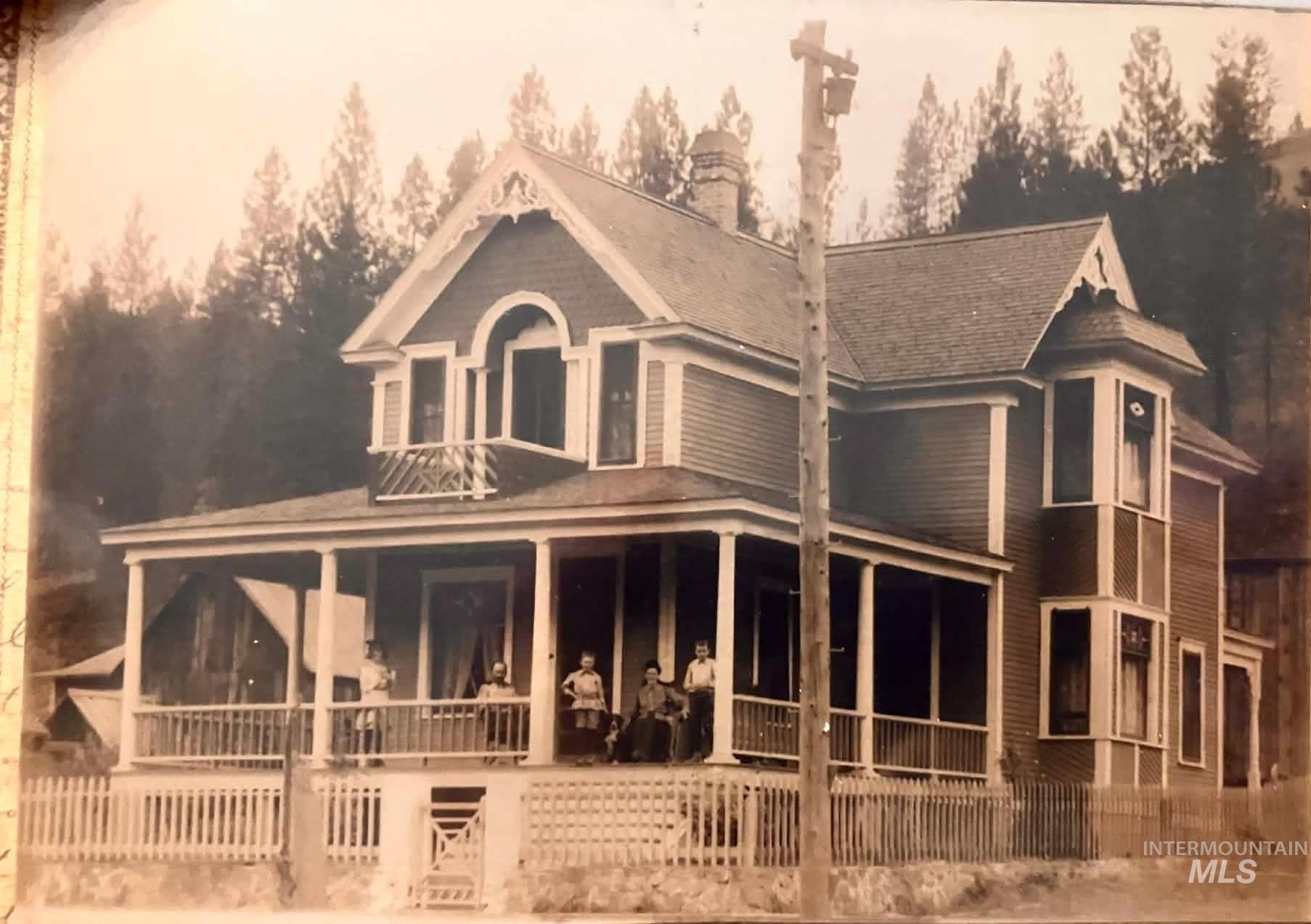 704 Riverside Avenue Orofino, ID 83544 - Photo 3 of 24 Victorian architecture featuring a full-width covered front porch, an upper-level arched window with balcony, a prominent bay window, and a white picket fence