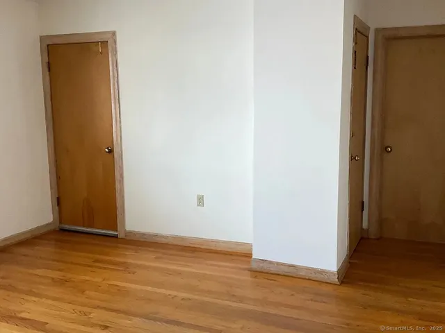 a view of an empty room with wooden floor and closet