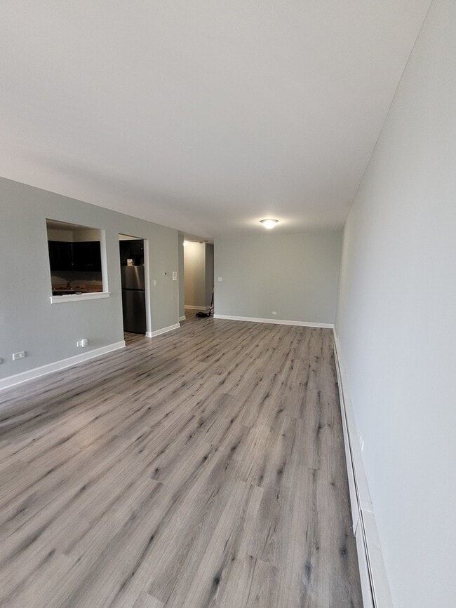 157 North Gregory Street, Unit 14 Aurora, IL 60504 - Photo 3 of 15 a view of an empty room with wooden floor and a window