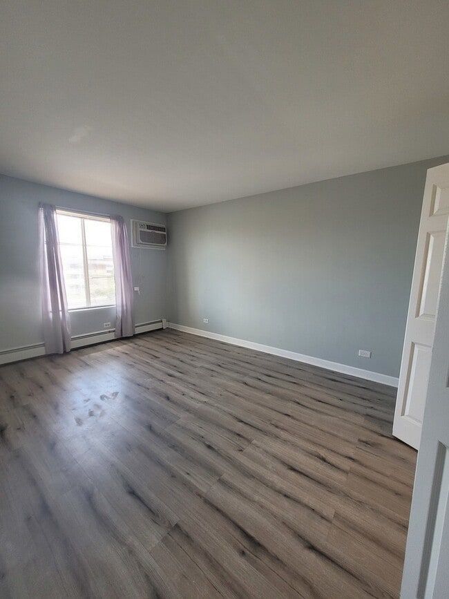 157 North Gregory Street, Unit 14 Aurora, IL 60504 - Photo 4 of 15 an empty room with wooden floor and windows