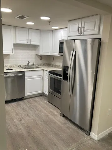 a kitchen with stainless steel appliances granite countertop a refrigerator sink and microwave