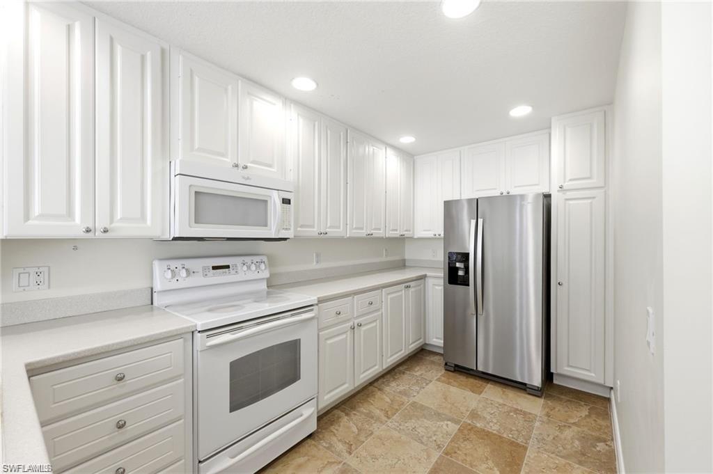 8108 Josefa Way Naples, FL 34114 - Photo 7 of 49 Kitchen with white appliances, white cabinetry, light countertops, recessed lighting, and stone finish floors