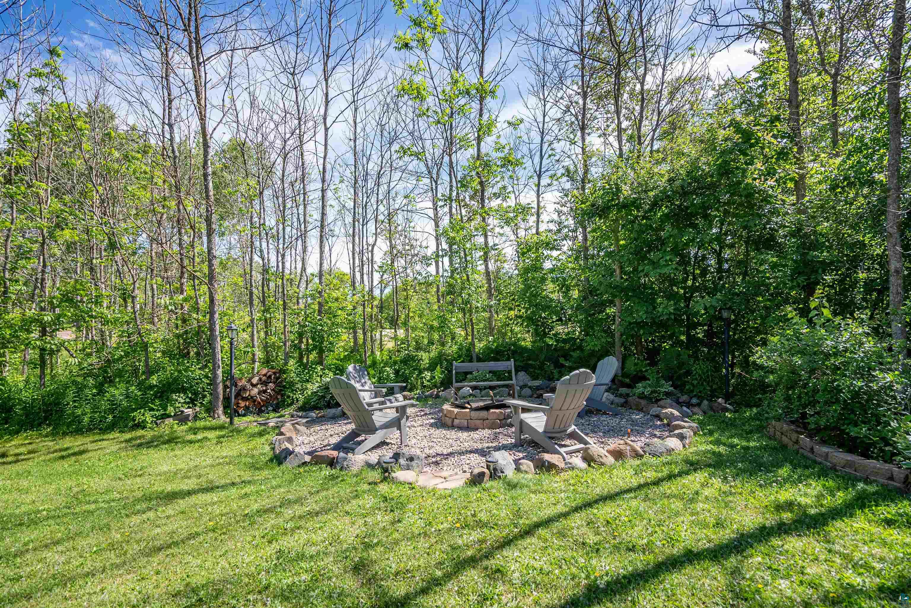 4809 Oak Ridge Drive Hermantown, MN 55811 - Photo 58 of 67 Expansive backyard featuring a circular fire pit with a stone surround, gravel base, and a brick-lined interior