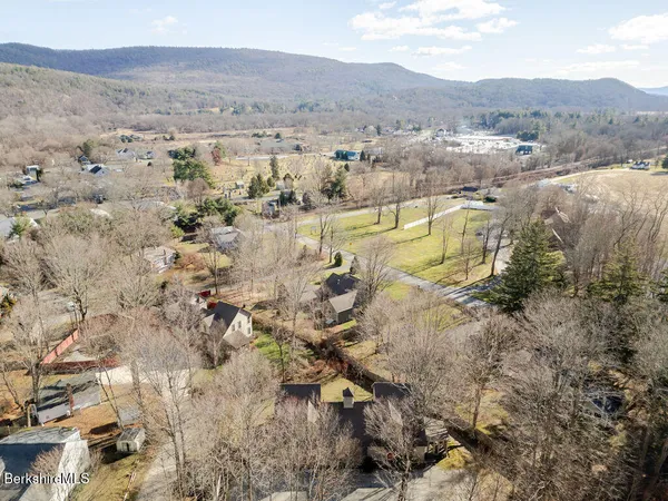 an aerial view of residential houses with outdoor space and trees
