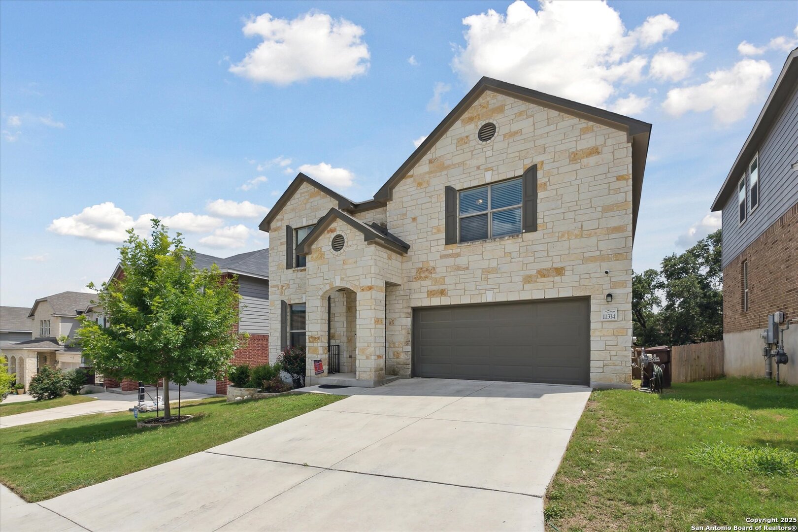 11314 Hill Top Bend Helotes, TX 78023 - Photo 4 of 49 a front view of a house with a yard and garage