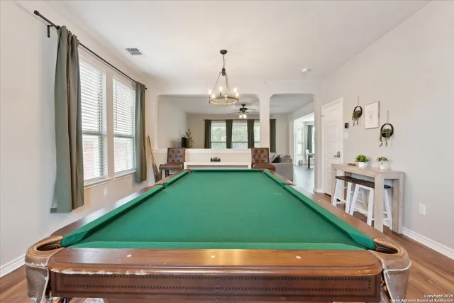 a room with pool table windows and a chandelier