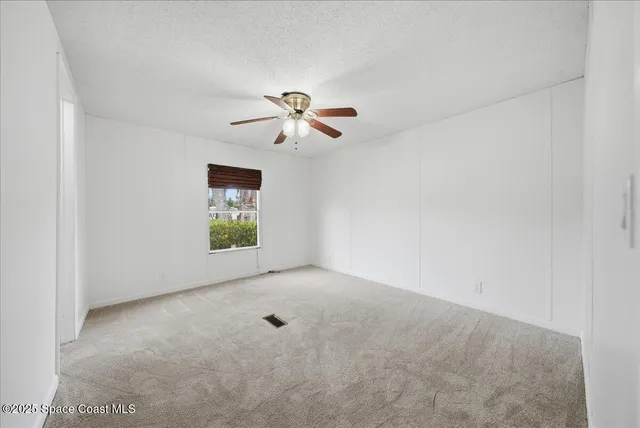 an empty room with windows and chandelier fan