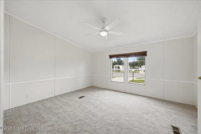 an empty room with a window and a ceiling fan