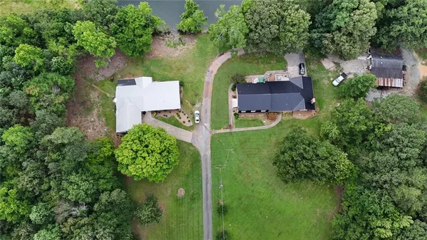 an aerial view of a house with a yard and trees all around